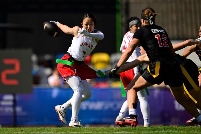 Japan's Yurika Rokukawa (L) and Canada's Sabrina Gervais fight for the ball during the women's match between Japan and Canada at the "IFAF World Flag" World Championship in flag football in Duesseldorf, western Germany, on August 14, 2026. (Photo by Ina FASSBENDER / AFP)