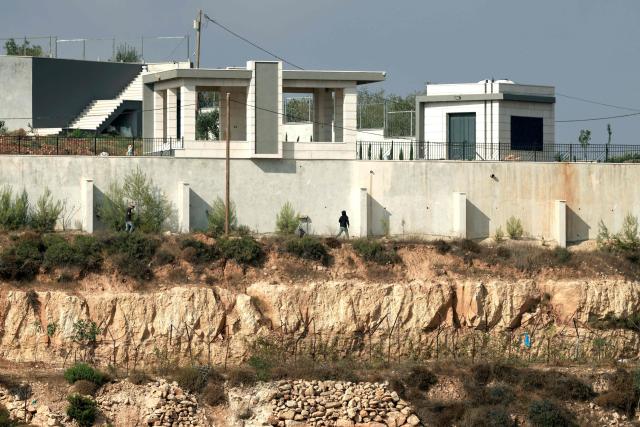 Israeli settlers walk along the perimeters of the garden wall of a besieged Palestinian home in the village of Qusra, south of the city Nablus, in the Israeli-occupied West Bank, on August 14, 2026, nearly a week after the settlers began blockading Palestinian homes defying attempts by the Israeli military to remove them. Activists attempted to deliver supplies to Palestinians under an almost week-long Israeli settler siege in the West Bank on August 14, with the Israeli military again deployed at the flashpoint site. All Israeli settlements in the West Bank, which has been occupied since 1967, are illegal under international law, with Palestinians in the Israeli-occupied West Bank gripped by almost daily violence involving Israeli troops and settlers since the start of the Gaza war in October 2023. (Photo by Jaafar ASHTIYEH / AFP)