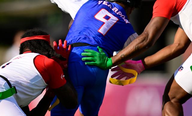 US players tackle a player of American Samoa during the men's match between American Samoa and the US at the "IFAF World Flag" World Championship in flag football in Duesseldorf, western Germany, on August 14, 2026. (Photo by Ina FASSBENDER / AFP)