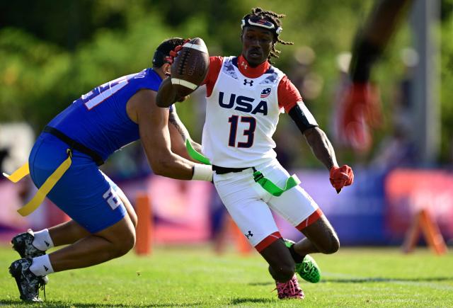 American Samoa's London Constantine Teidemann Iakopo (L) and USA's Velton Brown Jr fight for the ball during the men's match between American Samoa and the USA at the "IFAF World Flag" World Championship in flag football in Duesseldorf, western Germany, on August 14, 2026. (Photo by Ina FASSBENDER / AFP)