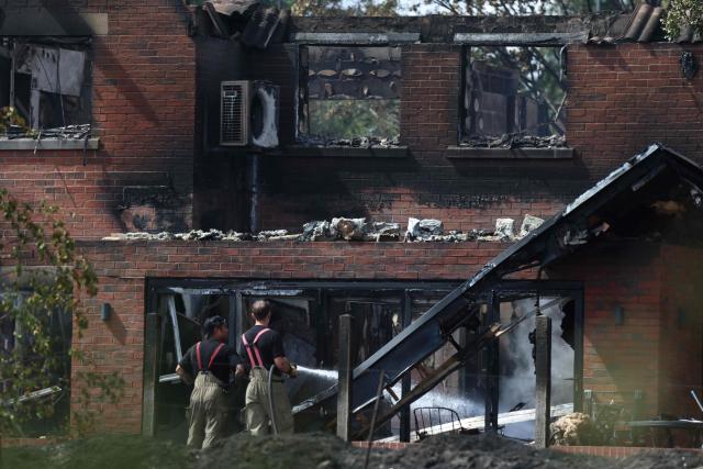 Firefighters puts water onto the smoldering ruins of a fire-damaged house, south of Stourbridge town centre in central England on August 14, 2026. Firefighters continued Friday to extinguish wildfires that began on August 13, tearing through several homes, with residents evacuated and "extensive" damage reported. (Photo by Darren Staples / AFP)