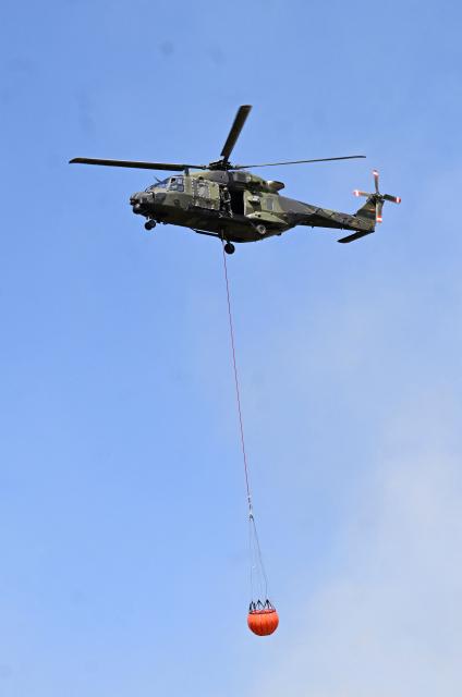 A German armed helicopters loads water to fight a forest fire in Huertgenwald, western Germany Friday, August 14, 2026. Around 1,800 people had to leave their homes in western Germany overnight as a wildfire spread nearby, officials said, with helicopters and army equipment deployed to help battle the flames. A district of the town of Huertgenwald near the Belgian and Dutch borders was evacuated after the fire expanded from 25 hectares (around 60 acres) to 300 hectares by Friday morning. (Photo by Roberto Pfeil / AFP)