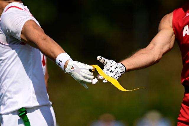 Players of Japan and Austria hand over a band during the men's match between Austria and Japan at the "IFAF World Flag" World Championship in flag football in Duesseldorf, western Germany, on August 14, 2026. (Photo by Ina FASSBENDER / AFP)