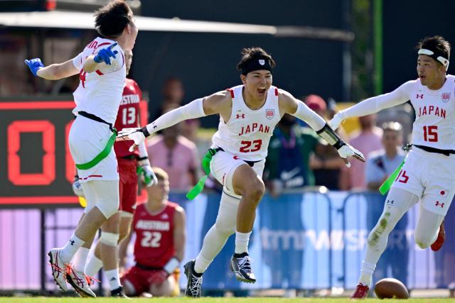 Japan's Ryota Okuda (C), Japan's Kento Nishida (L) and Japan's Ryohei Uematsu celebrate during the men's match between Austria and Japan at the "IFAF World Flag" World Championship in flag football in Duesseldorf, western Germany, on August 14, 2026. (Photo by Ina FASSBENDER / AFP)