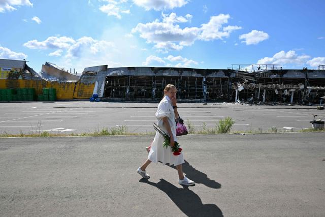 A woman walks past a burned DIY and construction materials mall following an overnight attack, which local Russian-installed officials called Ukrainian drone strikes, in Yenakiyeve in the Donetsk region, Russian-controlled Ukraine, on August 14, 2026, amid the ongoing Russian-Ukrainian conflict. (Photo by AFP)