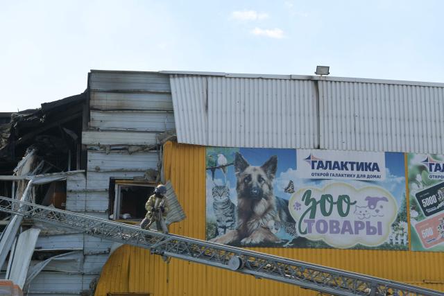 Firefighters work on the grounds of a burned DIY and construction materials mall following an overnight attack, which local Russian-installed officials called Ukrainian drone strikes, in Yenakiyeve in the Donetsk region, Russian-controlled Ukraine, on August 14, 2026, amid the ongoing Russian-Ukrainian conflict. (Photo by AFP)