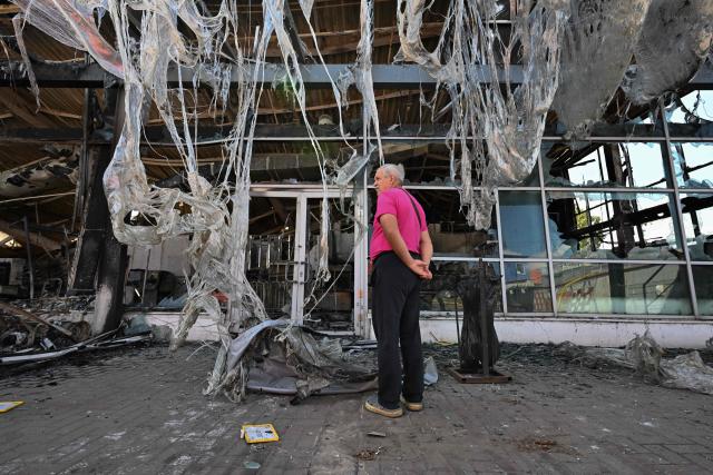 A man inspects damages of a burned DIY and construction materials mall following an overnight attack, which local Russian-installed officials called Ukrainian drone strikes, in Yenakiyeve in the Donetsk region, Russian-controlled Ukraine, on August 14, 2026, amid the ongoing Russian-Ukrainian conflict. (Photo by AFP)