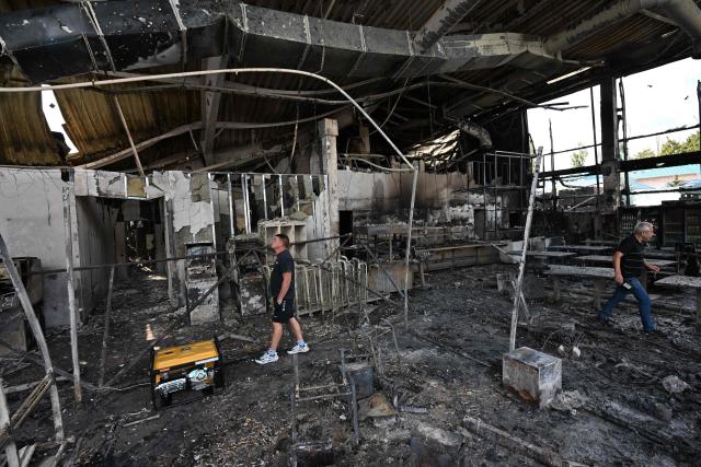 Men inspect damages inside a burned DIY and construction materials mall following an overnight attack, which local Russian-installed officials called Ukrainian drone strikes, in Yenakiyeve in the Donetsk region, Russian-controlled Ukraine, on August 14, 2026, amid the ongoing Russian-Ukrainian conflict. (Photo by AFP)