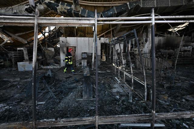 Firefighters work on the grounds of a burned DIY and construction materials mall following an overnight attack, which local Russian-installed officials called Ukrainian drone strikes, in Yenakiyeve in the Donetsk region, Russian-controlled Ukraine, on August 14, 2026, amid the ongoing Russian-Ukrainian conflict. (Photo by AFP)