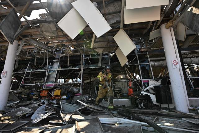 Firefighters work on the grounds of a burned DIY and construction materials mall following an overnight attack, which local Russian-installed officials called Ukrainian drone strikes, in Yenakiyeve in the Donetsk region, Russian-controlled Ukraine, on August 14, 2026, amid the ongoing Russian-Ukrainian conflict. (Photo by AFP)