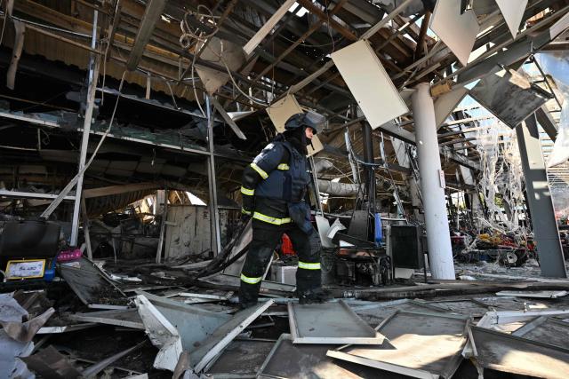 Firefighters work on the grounds of a burned DIY and construction materials mall following an overnight attack, which local Russian-installed officials called Ukrainian drone strikes, in Yenakiyeve in the Donetsk region, Russian-controlled Ukraine, on August 14, 2026, amid the ongoing Russian-Ukrainian conflict. (Photo by AFP)