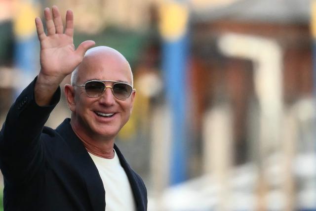 (FILES) US founder of Amazon, Jeff Bezos waves as he leaves the Aman Hotel in Venice on June 25, 2025. Liverpool's owners, August 14,  have agreed to sell a minority stake in the Premier League club to a consortium including Amazon founder Jeff Bezos. (Photo by Marco BERTORELLO / AFP)