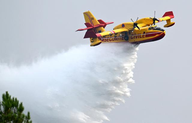 A French Civil Security Canadair CL-415 firefighting aircraft douses water over trees in a forest in Luglon, south-western France on August 14, 2026. (Photo by Gaizka IROZ / AFP)