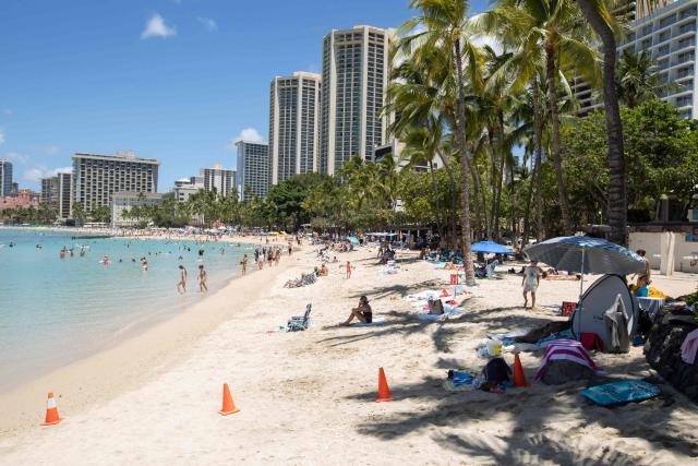 People are seen on Waikiki Beach in Honolulu, Hawaii, on August 14, 2026. A strengthening tropical storm named Lala is set to hit Hawaii's Big Island with hurricane force on Saturday, bringing dangerous winds, rainfall and surf as the state's governor declared a state of emergency. (Photo by Eugene Tanner / AFP)