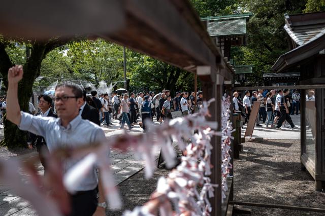 People arrive to pay their respect during a visit to the Yasukuni Shrine in Tokyo on August 15, 2026, on the 81st anniversary of Japan's surrender in World War II. Yasukuni is dedicated to 2.5 million war dead, mostly Japanese, including convicted war criminals involved in Imperial Japan's invasion and occupation of parts of Asia in the 1930s and 1940s. (Photo by Philip FONG / AFP)