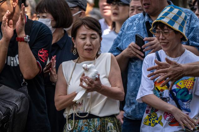 A woman holds a white dove, the sympol of peace, before being released as a tribute to the war dead at the Yasukuni Shrine in Tokyo on August 15, 2026, on the 81st anniversary of Japan's surrender in World War II. (Photo by Philip FONG / AFP)