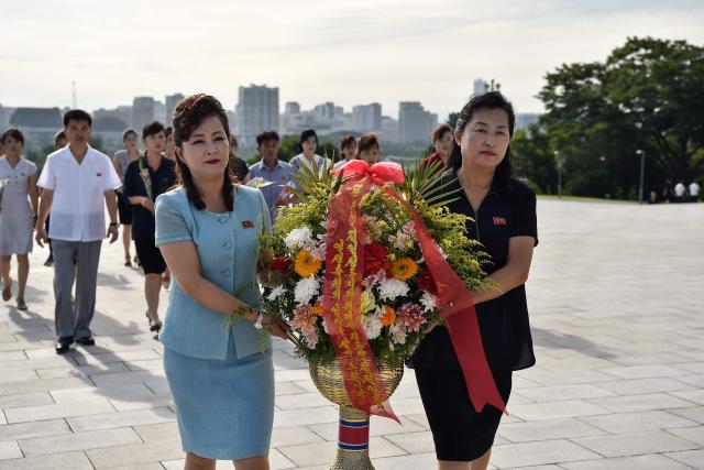 Women carry flowers as they prepare to pay their respect before the statues of late North Korean leaders Kim Il Sung and Kim Jong Il on Mansu Hill in Pyongyang on August 15, 2026, as North Korea marks its 81st National Liberation Day commemorating the end of Japanese colonial rule at the end of World War II. (Photo by KIM Won Jin / AFP)