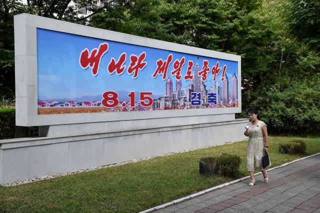 A woman walks past a billboard in Pyongyang on August 15, 2026, as North Korea marks its 81st National Liberation Day commemorating the end of Japanese colonial rule at the end of World War II. (Photo by KIM Won Jin / AFP)