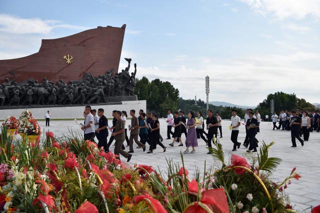 People carry flowers as they prepare to pay their respect before the statues of late North Korean leaders Kim Il Sung and Kim Jong Il on Mansu Hill in Pyongyang on August 15, 2026, as North Korea marks its 81st National Liberation Day commemorating the end of Japanese colonial rule at the end of World War II. (Photo by KIM Won Jin / AFP)