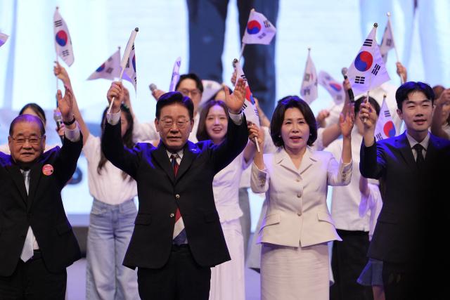South Korean President Lee Jae Myung (centre L) and his wife Kim Hea Kyung (centre R) wave the national flags during a ceremony to celebrate the 81st anniversary of the Korean Liberation Day in Seoul on August 15, 2026. (Photo by Lee Jin-man / POOL / AFP)