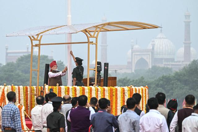India's Prime Minister Narendra Modi (L, top) hoists the Indian national flag from the ramparts of the Red Fort during the celebrations to mark the country's Independence Day in New Delhi on August 15, 2026. (Photo by Sajjad HUSSAIN / AFP)