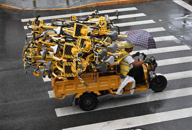 A worker rides a tricycle motor carrying shared bicycles in Beijing on August 15, 2026. (Photo by ADEK BERRY / AFP)