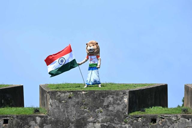 A cricket fan holds India's national flag atop the iconic Galle fort while watching the first day of the first Test cricket match between Sri Lanka and India at the Galle International Stadium in Galle on August 15, 2026. (Photo by Ishara S. KODIKARA / AFP)