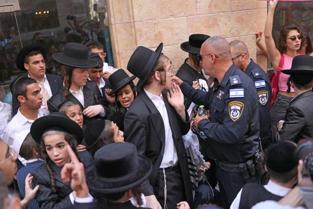 Ultra-Orthodox protesters demonstrate against Cafe Basimta operating on Shabbat, the weekly Jewish day of rest, as some argue with Israeli police as secular activists (R) stage a counter-protest in support of the cafe, in central Jerusalem on August 15, 2026. (Photo by AHMAD GHARABLI / AFP)