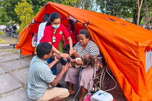 A young patient is treated next to a temporary medical tent set up due to fears of aftershocks in Maumere on Flores Island on August 15, 2026, following a 7.7-magnitude earthquake. Rescuers combed through debris for survivors after a powerful earthquake struck off Indonesia's Flores Island on August 15, killing at least 38 people, according to a disaster official. (Photo by ARNOLD WELIANTO / AFP)