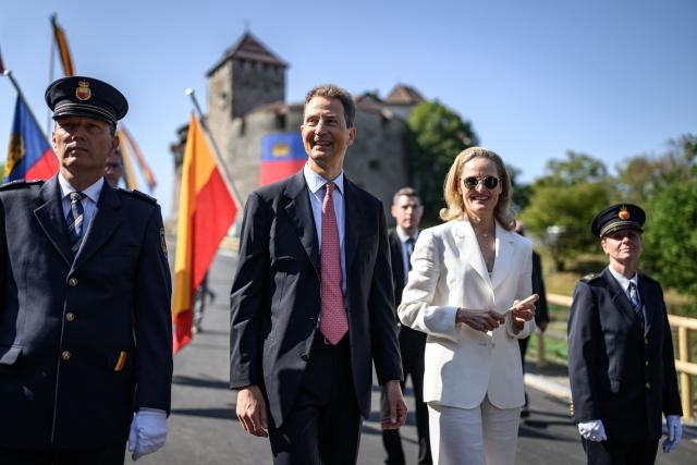 Liechtenstein's Hereditary Prince Alois (C) and his wife Hereditary Princess Sophie look on with the Vaduz Castle as background during Liechtenstein's National Day celebrations in Vaduz, on August 15, 2026. Each year on National Day, members of the Princely Family join thousands of residents and visitors for official ceremonies and public celebrations. (Photo by Fabrice COFFRINI / AFP)