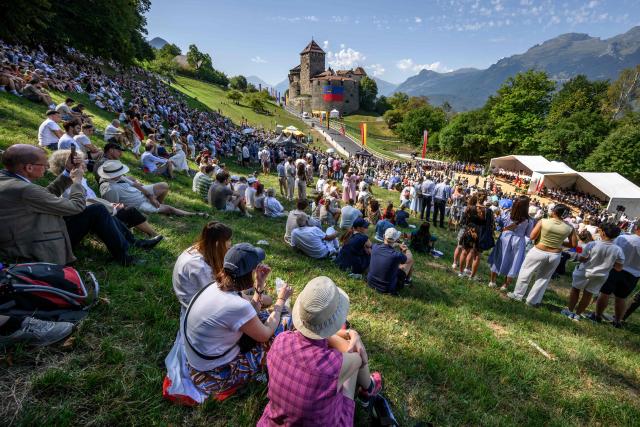People gather on the slopes below Vaduz Castle, the palace and official residence of the Prince of Liechtenstein, during Liechtenstein's National Day celebrations in Vaduz, on August 15, 2026. Each year on National Day, members of the Princely Family join thousands of residents and visitors for official ceremonies and public celebrations. (Photo by Fabrice COFFRINI / AFP)