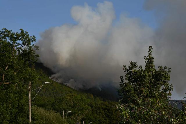 Smoke rises from burning moorland near a residential road, close to Ebbw Vale, in south Wales on August 15, 2026. Around 200 military personnel have been deployed to a large area across South Wales to help battle wildfires. (Photo by JUSTIN TALLIS / AFP)