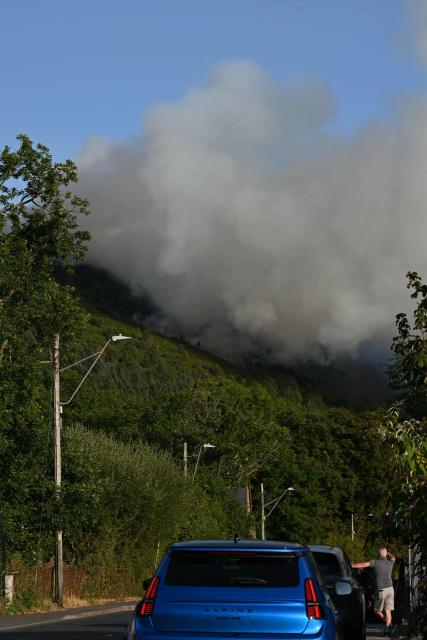 Smoke rises from burning moorland near a residential road, close to Ebbw Vale, in south Wales on August 15, 2026. Around 200 military personnel have been deployed to a large area across South Wales to help battle wildfires. (Photo by JUSTIN TALLIS / AFP)
