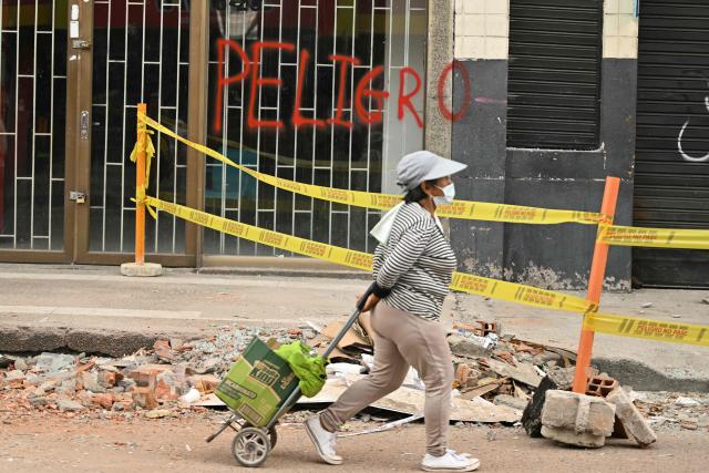 A local walks past a building reading "Danger" (Peligro) in Pereira, Colombia, on August 15, 2026, days after a 7.4 earthquake. At least 287 people have died, thousands have been injured and about 379 remain unaccounted for, while the chances of finding earthquake survivors have dropped sharply since the critical 72-hour window passed. (Photo by Luis ACOSTA / AFP)