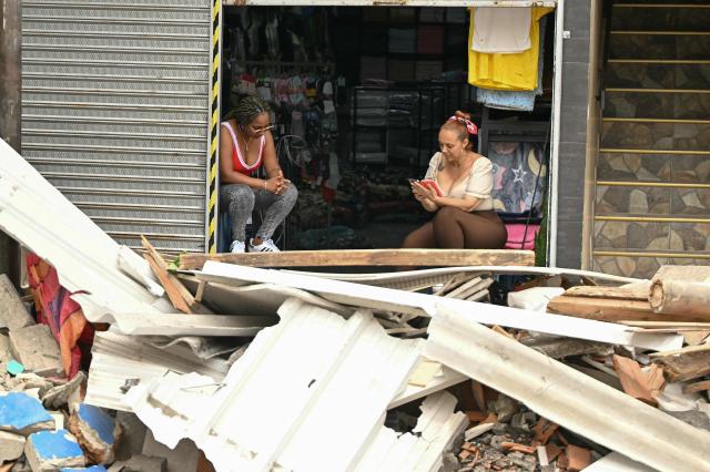 Two women sit at a store doorstep in Pereira, Colombia, on August 15, 2026, days after a 7.4 earthquake. At least 287 people have died, thousands have been injured and about 379 remain unaccounted for, while the chances of finding earthquake survivors have dropped sharply since the critical 72-hour window passed. (Photo by Luis ACOSTA / AFP)