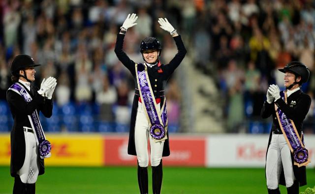 (L-R) Second placed Denmark's Cathrine Laudrup-Dufour, winner Great Britain's Charlotte Fry and third placed Germany's Isabell Werth celebrate on the podium of the Grand Prix Freestyle Individual Final of the FEI Dressage World Championship equestrian event on August 15, 2026 in Aachen, western Germany. (Photo by INA FASSBENDER / AFP)
