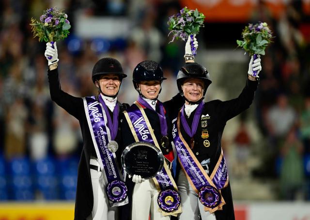 (L-R) Second placed Denmark's Cathrine Laudrup-Dufour, winner Great Britain's Charlotte Fry and third placed Germany's Isabell Werth celebrate on the podium of the Grand Prix Freestyle Individual Final of the FEI Dressage World Championship equestrian event on August 15, 2026 in Aachen, western Germany. (Photo by INA FASSBENDER / AFP)