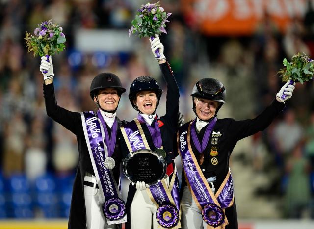 (L-R) Second placed Denmark's Cathrine Laudrup-Dufour, winner Great Britain's Charlotte Fry and third placed Germany's Isabell Werth celebrate on the podium of the Grand Prix Freestyle Individual Final of the FEI Dressage World Championship equestrian event on August 15, 2026 in Aachen, western Germany. (Photo by Ina FASSBENDER / AFP)