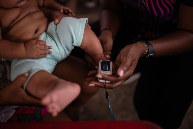 A health worker attends to a baby in the Santo Domingo of Quibdo, Choco department, Colombia, on August 15, 2026, days after a 7.4- magnitude earthquake. At least 287 people have died, thousands have been injured and about 379 remain unaccounted for, as the chances of finding earthquake survivors have dropped sharply since the critical 72-hour window passed, though volunteers and rescue crews continue digging through the rubble for any signs of life. (Photo by ESTEBAN VEGA LA-ROTTA / AFP)