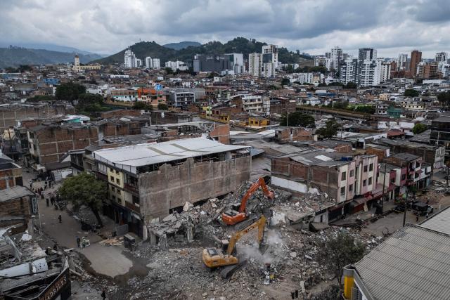 An aerial view shows a backhoe removing debris from collapsed buildings in Pereira, Colombia, on August 15, 2026, days after a 7.4 earthquake. At least 287 people have died, thousands have been injured and about 379 remain unaccounted for, while the chances of finding earthquake survivors have dropped sharply since the critical 72-hour window passed. (Photo by Luis ACOSTA / AFP)