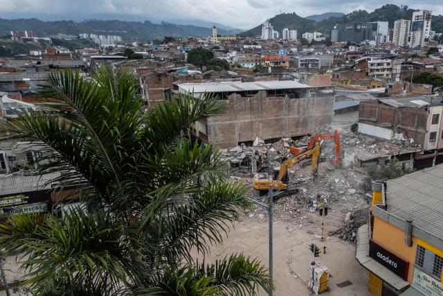 An aerial view shows a backhoe removing debris from collapsed buildings in Pereira, Colombia, on August 15, 2026, days after a 7.4 earthquake. At least 287 people have died, thousands have been injured and about 379 remain unaccounted for, while the chances of finding earthquake survivors have dropped sharply since the critical 72-hour window passed. (Photo by Luis ACOSTA / AFP)
