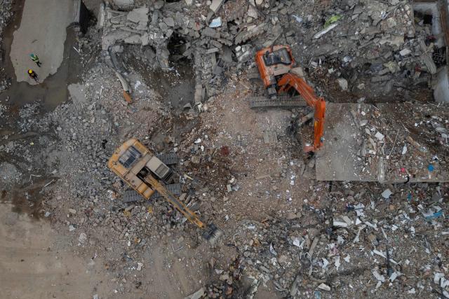 An aerial view shows a backhoe removing debris from collapsed buildings in Pereira, Colombia, on August 15, 2026, days after a 7.4 earthquake. At least 287 people have died, thousands have been injured and about 379 remain unaccounted for, while the chances of finding earthquake survivors have dropped sharply since the critical 72-hour window passed. (Photo by Luis ACOSTA / AFP)