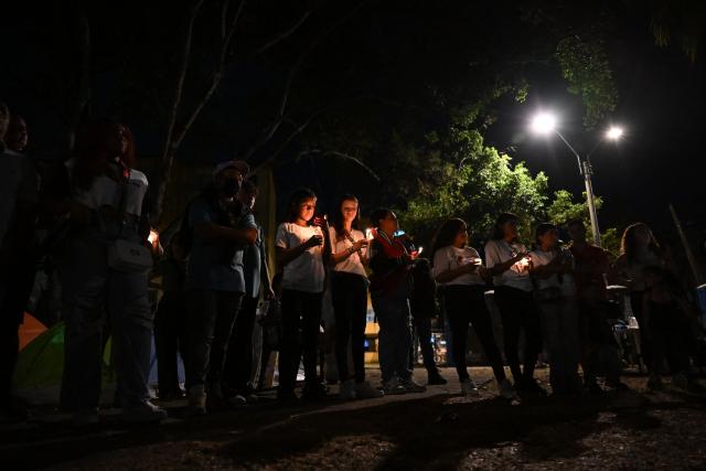 People hold candles during a vigil honouring the victims after a 7.4 earthquake in Cali, Colombia on August 15, 2026. At least 287 people have died, thousands have been injured and about 379 remain unaccounted for, as the chances of finding earthquake survivors have dropped sharply since the critical 72-hour window passed, though volunteers and rescue crews continue digging through the rubble for any signs of life. (Photo by Raul ARBOLEDA / AFP)