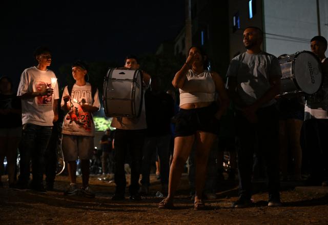 People hold candles during a vigil honouring the victims after a 7.4 earthquake in Cali, Colombia on August 15, 2026. At least 287 people have died, thousands have been injured and about 379 remain unaccounted for, as the chances of finding earthquake survivors have dropped sharply since the critical 72-hour window passed, though volunteers and rescue crews continue digging through the rubble for any signs of life. (Photo by Raul ARBOLEDA / AFP)