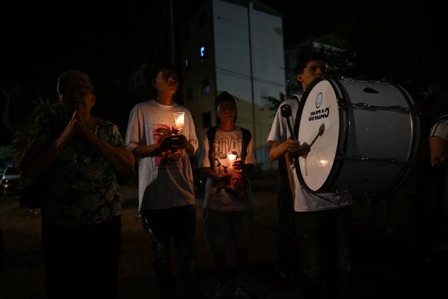 People hold candles during a vigil honouring the victims after a 7.4 earthquake in Cali, Colombia on August 15, 2026. At least 287 people have died, thousands have been injured and about 379 remain unaccounted for, as the chances of finding earthquake survivors have dropped sharply since the critical 72-hour window passed, though volunteers and rescue crews continue digging through the rubble for any signs of life. (Photo by Raul ARBOLEDA / AFP)