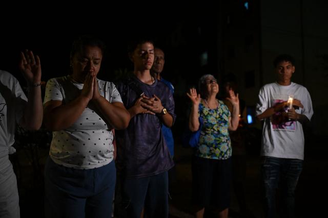 People pray during a vigil honouring the victims after a 7.4 earthquake in Cali, Colombia on August 15, 2026. At least 287 people have died, thousands have been injured and about 379 remain unaccounted for, as the chances of finding earthquake survivors have dropped sharply since the critical 72-hour window passed, though volunteers and rescue crews continue digging through the rubble for any signs of life. (Photo by Raul ARBOLEDA / AFP)