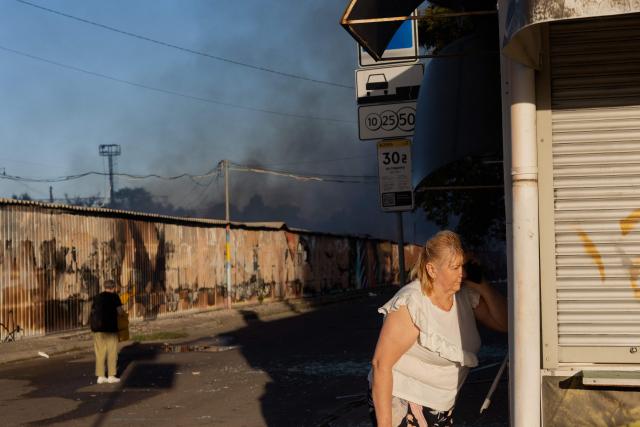 A woman (R) talks on the phone at the site of a Russian strike in Kyiv on August 16, 2026, amid the Russian invasion of Ukraine. Russian strikes killed one person and wounded at least seven others in Ukraine, authorities said August 16, while Moscow officials reported downing more than 100 drones heading towards the capital. (Photo by Tetiana DZHAFAROVA / AFP)