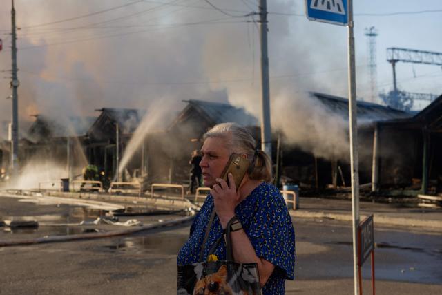 A woman talks on the phone at the site of a Russian strike in Kyiv on August 16, 2026, amid the Russian invasion of Ukraine. Russian strikes killed one person and wounded at least seven others in Ukraine, authorities said August 16, while Moscow officials reported downing more than 100 drones heading towards the capital. (Photo by Tetiana DZHAFAROVA / AFP)
