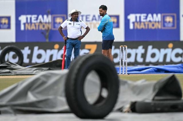 Sri Lanka's captain Dhananjaya de Silva (R) inspects the pitch after rain delayed the start of play on second day of the first Test cricket match between Sri Lanka and India at the Galle International Stadium in Galle on August 16, 2026. (Photo by Ishara S. KODIKARA / AFP)