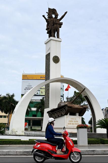 A woman rides a motorcycle past the Buon Ma Thuot Victory Monument in Dak Lak province on August 16, 2026. (Photo by Nhac NGUYEN / AFP)